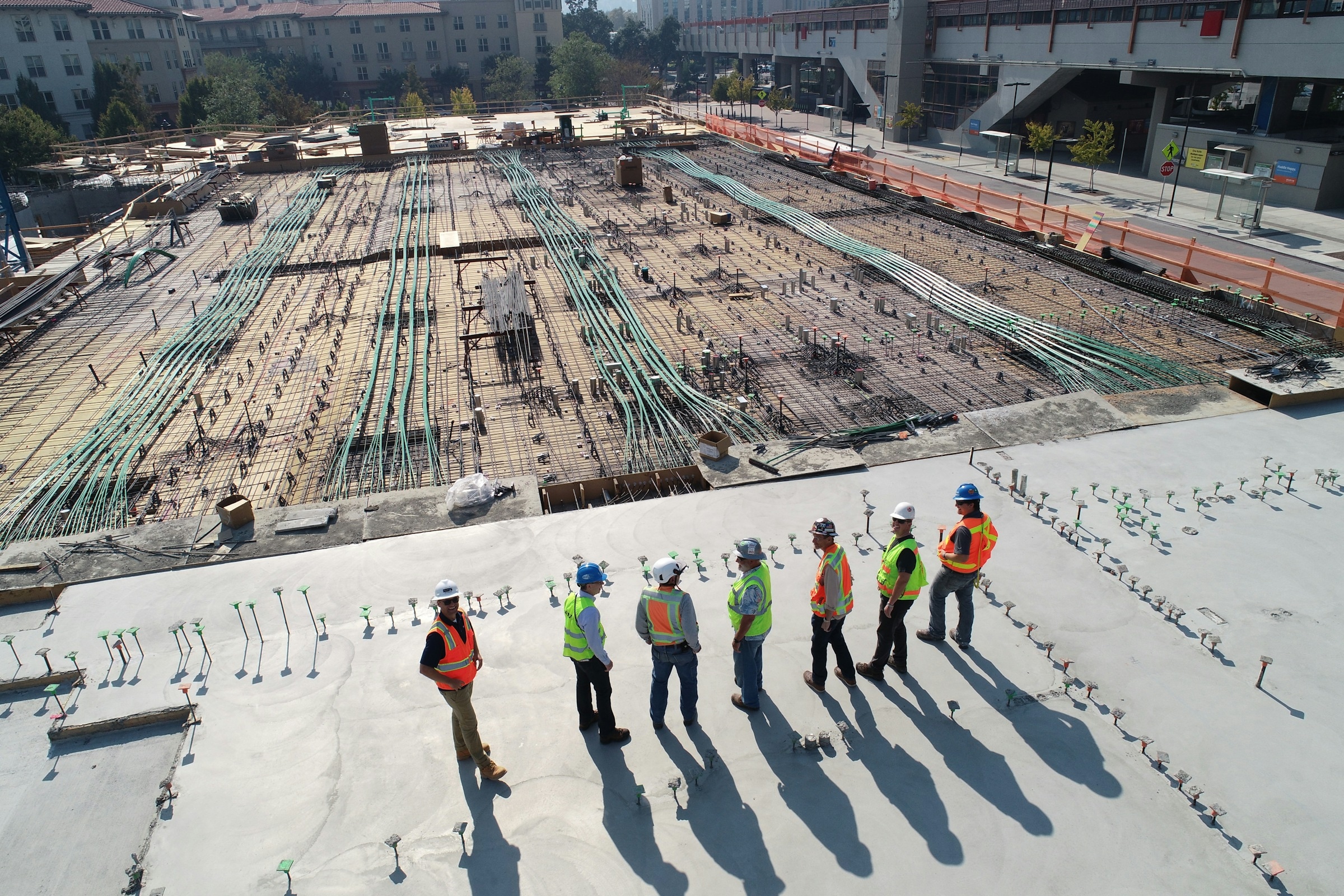 Equipo de obra con cascos y chalecos de seguridad sobre una estructura de hormigón en construcción